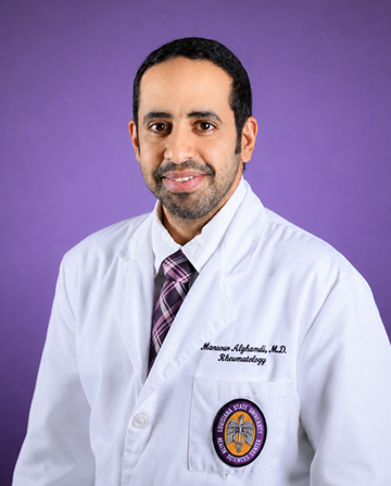 Professional studio portrait of a person wearing a white medical lab coat over a dress shirt and purple plaid tie, seated against a solid purple background. The lab coat displays an embroidered specialty designation and a university health sciences center emblem on the front pocket. The person is facing the camera in a formal head-and-shoulders pose.