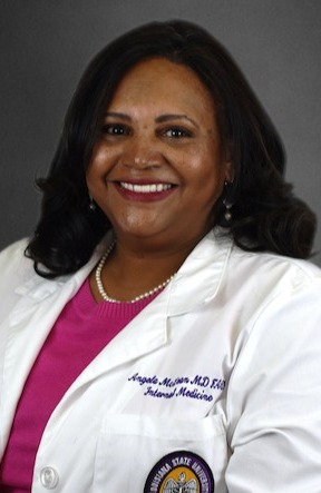 Professional headshot of a person wearing a white lab coat over a dark shirt and tie, facing the camera against a plain gray background. The person is centered in the frame, with a bald head and hair visible at the sides. The portrait is evenly lit and cropped from the chest up, in a typical corporate or medical-profile style.