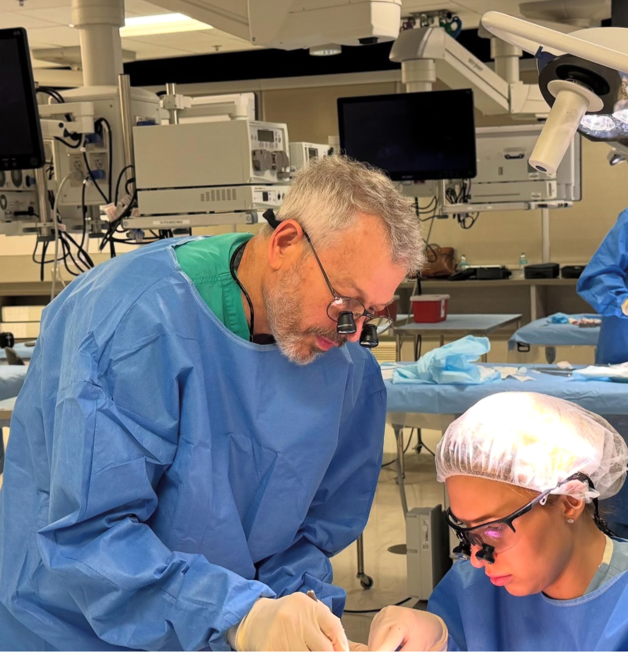 faculty and resident leaning over lab table wearing scrubs and scope glasses
