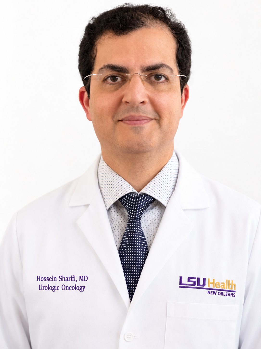 Professional headshot of a person wearing glasses, a white medical lab coat, a patterned dress shirt, and a dark blue tie, facing the camera against a light gray background. The lab coat displays the text “Hossein Sharifi, MD, Urologic Oncology” on the left side and the LSU Health New Orleans logo on the right side. The image is evenly lit and cropped from the chest up.